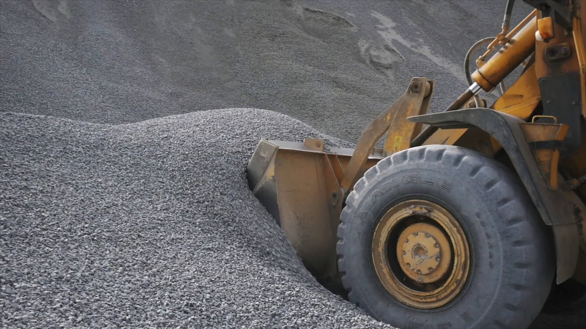 Loader bucket scooping a pile of gravel